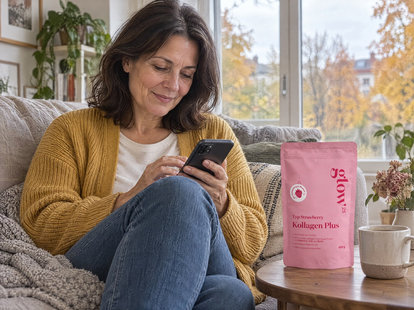 Vrouw in mosterdkleurig vest kiest op de bank op haar telefoon haar volgende levering, ernaast Collagen Plus Strawberry
